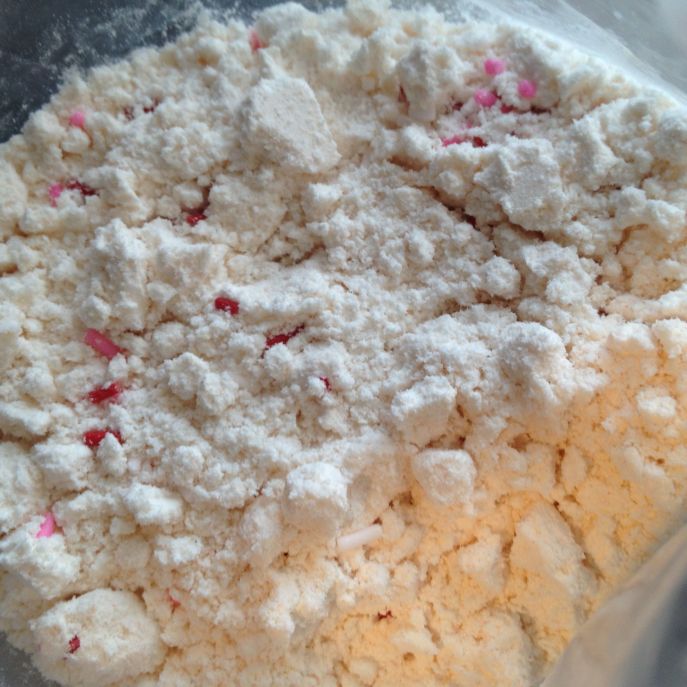 Red and pink sprinkles dot yellow cake mix.