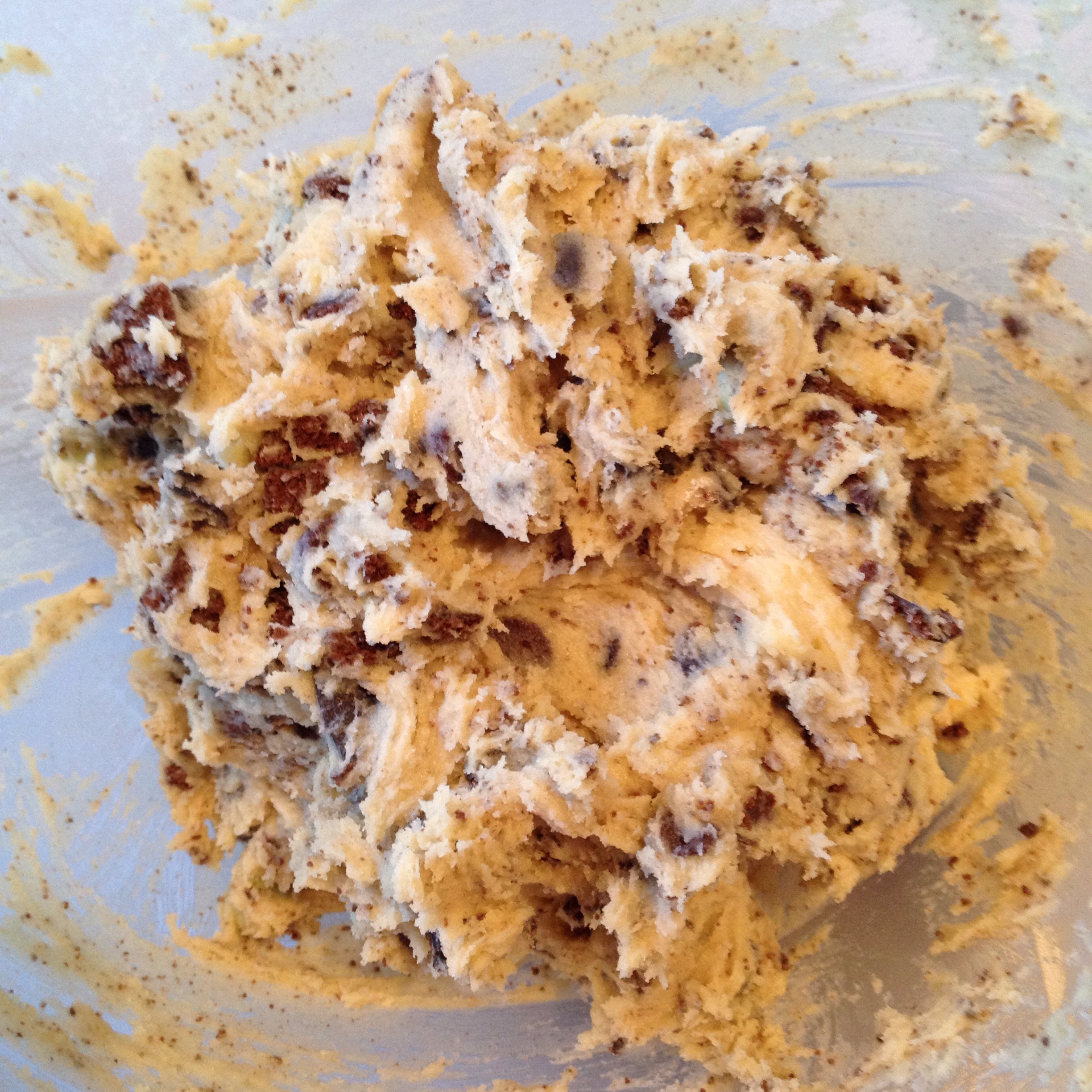 Cookie dough with chunks of cookie and chocolate chips sits in a bowl.